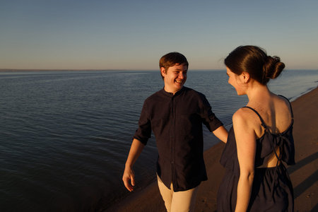 Portrait of a young happy couple in love on the background of the sea in the sunset lighting