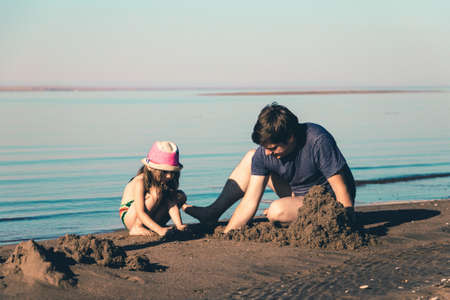 Father and his daughter build sand castles on the beach. Toned photoの写真素材