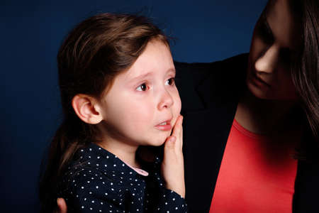 Little girl is upset and crying from resentment in her mother's arms.の写真素材