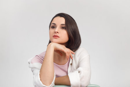 High-key studio portrait of a young dreaming woman in light clothes looking into the distance