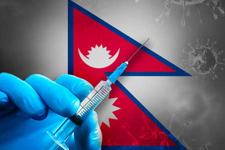 Nepal Covid-19 Vaccination Campaign. A hand in a blue rubber glove holds a syringe with covid-19 virus vaccine in front of Nepal flag. Coronavirus vaccination conceptの写真素材