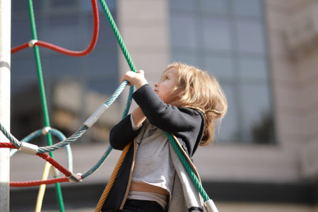 Cute little girl 3 - 5 years old at the urban playground on the background of a modern condominium....