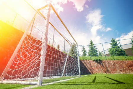 Football or soccer goal on an amateur small field, lens flare and blue skyの写真素材