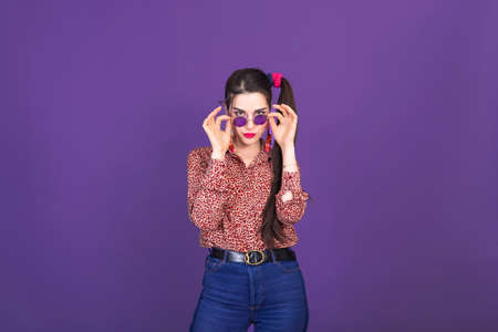 Pretty young woman in retro 90s fashion style over purple studio background.の写真素材