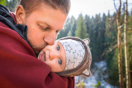 Father kisses his funny baby boy on a walk outdoor.の写真素材