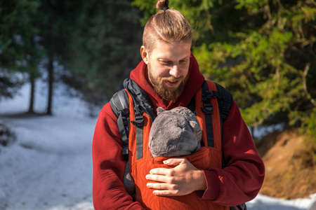 Young bearded father with his baby boy in ergonomic baby carrier in winter outdoor.の写真素材