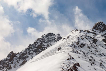 Snowy rocky mountains with avalanche protection barriers.の写真素材