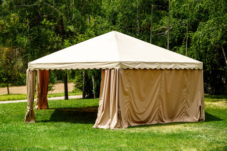 Beige canopy tent on green lawn garden.