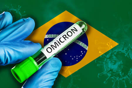 Brasil outbreak of omicron variant. A hand in a blue rubber glove holds a test tube with covid-19 virus omicron in front of Brasil flag. Omicron variant outbreak conceptの写真素材