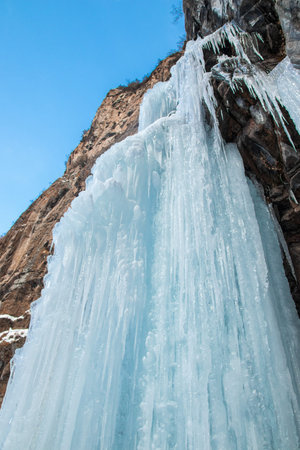 Frozen waterfall on rocky mountain in winter day in Almaty region.