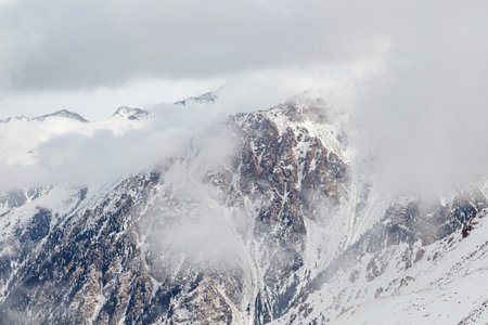 Snowy rocky mountains merging with the clouds.