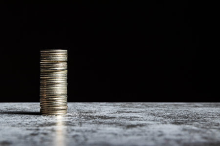 Stack of coins on grey table and black background. Venture capital concept with copy space.