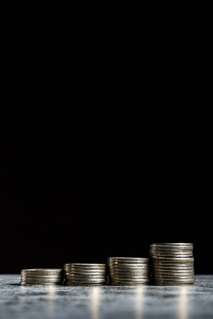 Stacks of coins on gray table and black background like growth financial symbol. Copy space, verticalの写真素材
