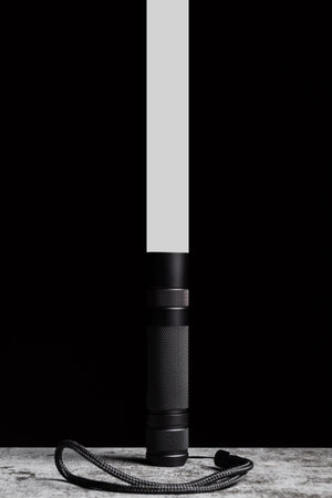 Flashlight stands on a table with a narrow beam of light upwards on a black background.の写真素材