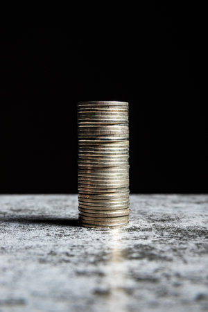 Stack of coins on grey table and black background.