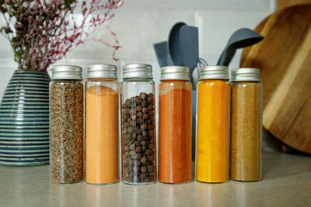 Different spices in glass transparent jars for spices on the table in home kitchen with copy space.の写真素材