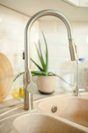 Big kitchen faucet on a stone home sink. selective soft focus.