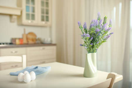 Fresh bouquet of wildflowers in a decorative vase on a home kitchen table in the early morning.の写真素材