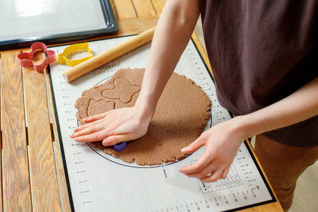 Woman hands cooking homemade cookies from rolled dough with culinary molds silicone baking mat.の写真素材