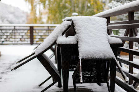 Freshly fallen snow on the furniture of the cafe's summer terrace, closing of the summer season.の写真素材