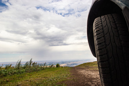 View of the wheel of a car on a high mountain off-road over the city.の写真素材