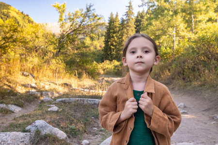 Adorable little girl hiking in the mountains outdoor forest on summer day.