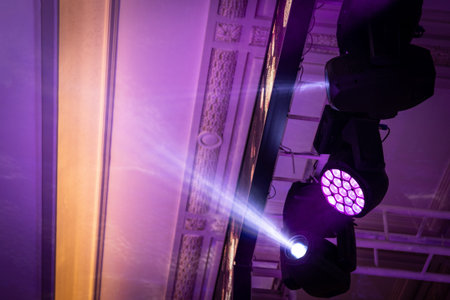 RGBW LED spotlight with moving head light and stage lighting hangs on a ceiling truss in a party...