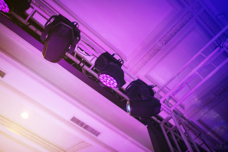 Light heads beam and wash hang on a truss above the ceiling.