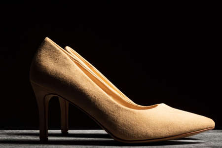 Suede women's shoes of beige color with heels on a dark background.の写真素材