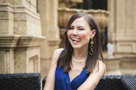 Funny pretty smiling with tongue woman in blue dress outdoor emotional portrait.の写真素材