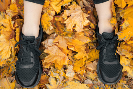 Close-up of casual woman sport shoes in the autumn leaves.