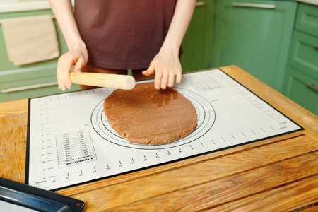 Rolling out shortcrust pastry for home bakery on a silicone baking mat on a wooden table.の写真素材