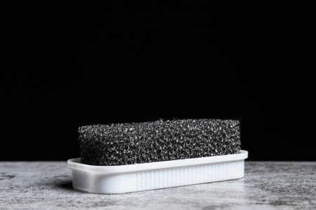 Foam sponge for suede shoes on a black background with copy space.