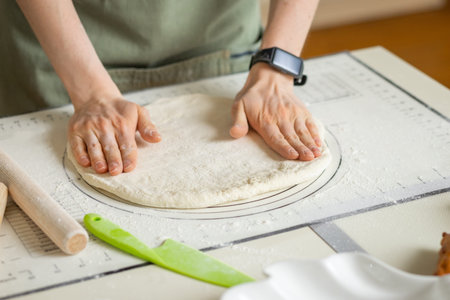 Woman hands with electronic bracelet cooking homemade pastry on silicone baking mat with markings...