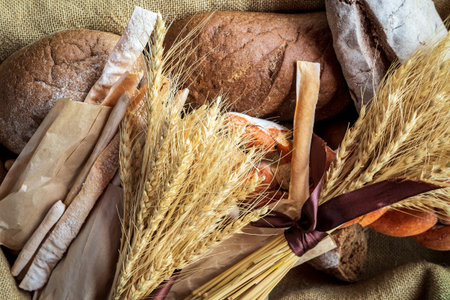Top view of a bouquet of wheat lying on fresh bread and other bakery products as a symbol of food...