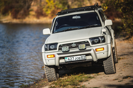 Japanese off-road used white car Toyota Hilux Surf on lake coast, car for fishing. Almaty,...