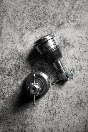 2 Ball joint lies on gray surface- Spare part for car suspension repair, top view, copy space, vertical.の写真素材