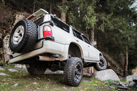 White off-road car in travel on mountain forest, Tuned reinforced suspension helps to overcome obstacles.の写真素材