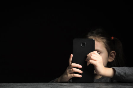 Kid gadget addiction and insomnia, psychological problems, black background, copy space.の写真素材