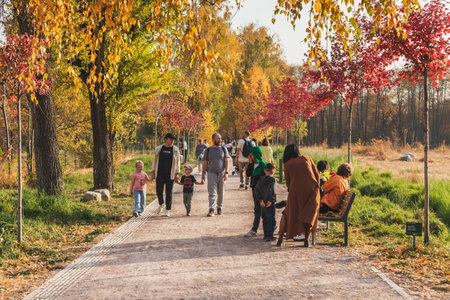 Families of people walk along the autumn alley of the Botanical Garden of the city of Almaty in Kazakhstan. Almaty, Kazakhstan - October 16, 2022のeditorial素材