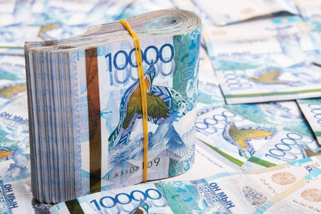 A pack of 10000 banknotes of Kazakhstan tenge, against the background of spread out Kazakhstani...