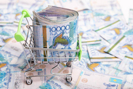 10000 Kazakhstan tenge in a shopping cart against the background of Kazakh money.