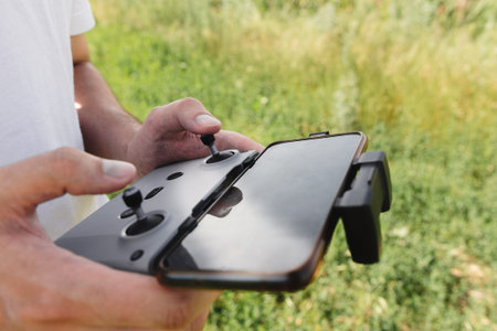 Control panel with a smartphone in the hands of a drone pilot outdoor.