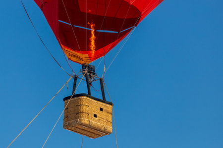 Empty basket from a red balloon against a clear blue sky.の写真素材