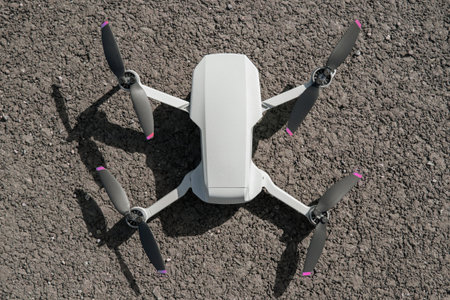 A modern drone, also known as a quadrocopter, stands on the pavement. ready to take off, top view.