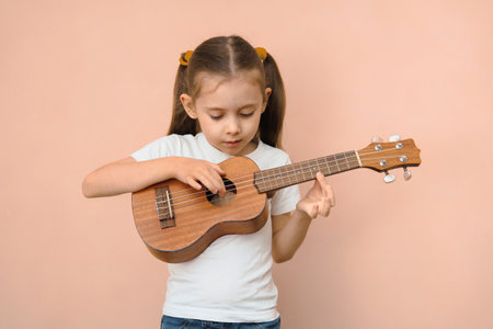 Preschool girl learning music by playing ukulele.の写真素材
