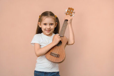 Caucasian smiling happy elementary school age girl learning music playing guitar.の写真素材