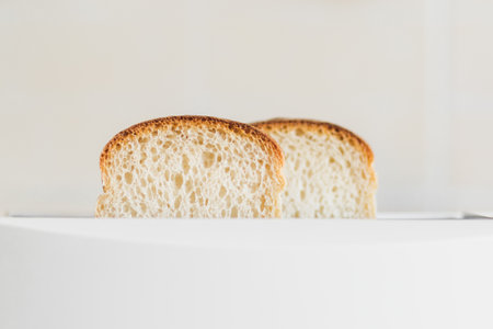 Front view on sliced fresh bread inserted into a white toaster, selective soft focus, copy spce.の写真素材