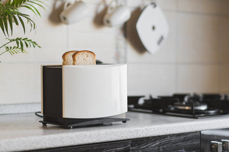 White toaster with sliced bread stands on the work surface of the kitchen table in the home interior.の写真素材