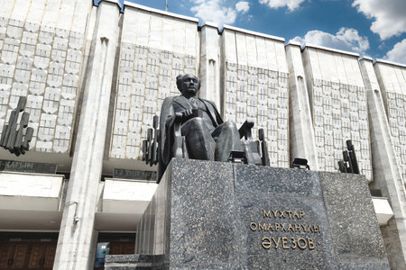 Facade Kazakh National Drama Theatre. M. Auezov with a sculpture of Auezov in front of him. Almaty, Kazakhstan - May 08, 2023のeditorial素材